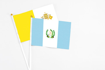 Guatemala and Vatican City stick flags on white background. High quality fabric, miniature national flag. Peaceful global concept.White floor for copy space.