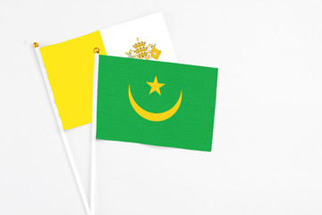 Mauritania and Vatican City stick flags on white background. High quality fabric, miniature national flag. Peaceful global concept.White floor for copy space.