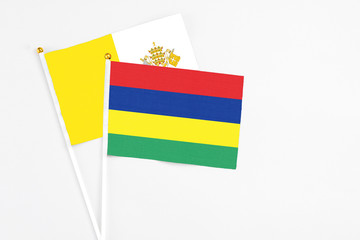 Mauritius and Vatican City stick flags on white background. High quality fabric, miniature national flag. Peaceful global concept.White floor for copy space.