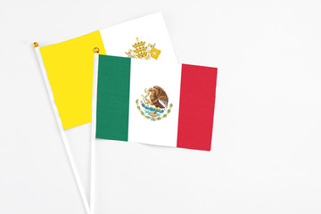 Mexico and Vatican City stick flags on white background. High quality fabric, miniature national flag. Peaceful global concept.White floor for copy space.