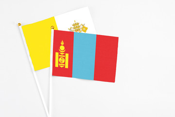 Fototapeta premium Mongolia and Vatican City stick flags on white background. High quality fabric, miniature national flag. Peaceful global concept.White floor for copy space.