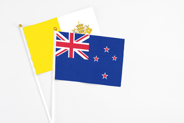 Fototapeta premium New Zealand and Vatican City stick flags on white background. High quality fabric, miniature national flag. Peaceful global concept.White floor for copy space.