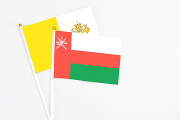 Fototapeta premium Oman and Vatican City stick flags on white background. High quality fabric, miniature national flag. Peaceful global concept.White floor for copy space.