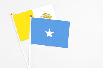 Somalia and Vatican City stick flags on white background. High quality fabric, miniature national flag. Peaceful global concept.White floor for copy space.