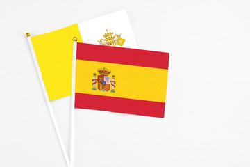 Spain and Vatican City stick flags on white background. High quality fabric, miniature national flag. Peaceful global concept.White floor for copy space.