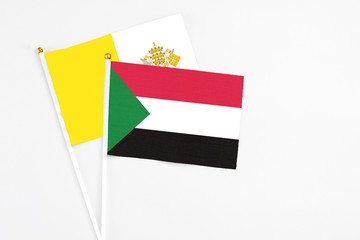 Sudan and Vatican City stick flags on white background. High quality fabric, miniature national flag. Peaceful global concept.White floor for copy space.