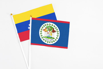 Belize and Venezuela stick flags on white background. High quality fabric, miniature national flag. Peaceful global concept.White floor for copy space.