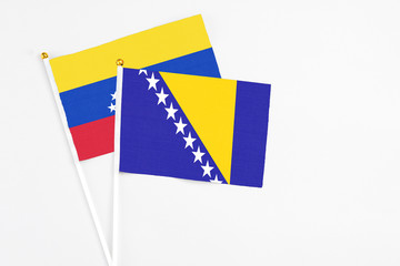 Bosnia Herzegovina and Venezuela stick flags on white background. High quality fabric, miniature national flag. Peaceful global concept.White floor for copy space.