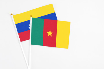 Cameroon and Venezuela stick flags on white background. High quality fabric, miniature national flag. Peaceful global concept.White floor for copy space.