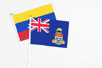 Fototapeta premium Cayman Islands and Venezuela stick flags on white background. High quality fabric, miniature national flag. Peaceful global concept.White floor for copy space.