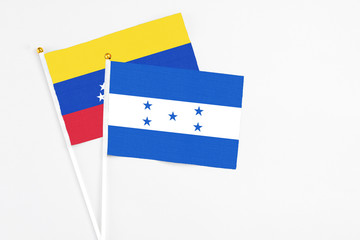 Fototapeta premium Honduras and Venezuela stick flags on white background. High quality fabric, miniature national flag. Peaceful global concept.White floor for copy space.