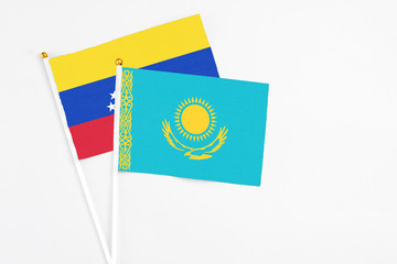 Kazakhstan and Venezuela stick flags on white background. High quality fabric, miniature national flag. Peaceful global concept.White floor for copy space.