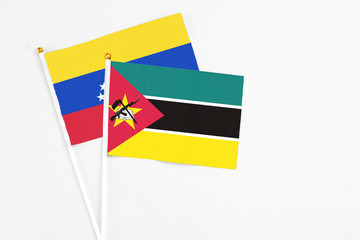 Mozambique and Venezuela stick flags on white background. High quality fabric, miniature national flag. Peaceful global concept.White floor for copy space.