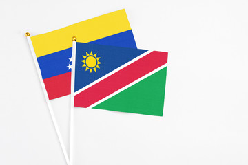 Namibia and Venezuela stick flags on white background. High quality fabric, miniature national flag. Peaceful global concept.White floor for copy space.