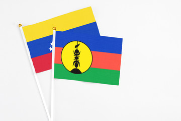 New Caledonia and Venezuela stick flags on white background. High quality fabric, miniature national flag. Peaceful global concept.White floor for copy space.