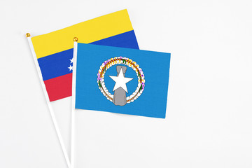 Northern Mariana Islands and Venezuela stick flags on white background. High quality fabric, miniature national flag. Peaceful global concept.White floor for copy space.