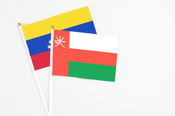 Oman and Venezuela stick flags on white background. High quality fabric, miniature national flag. Peaceful global concept.White floor for copy space.