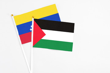 Palestine and Venezuela stick flags on white background. High quality fabric, miniature national flag. Peaceful global concept.White floor for copy space.