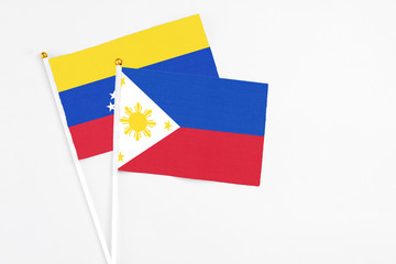 Philippines and Venezuela stick flags on white background. High quality fabric, miniature national flag. Peaceful global concept.White floor for copy space.