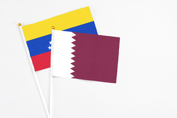 Qatar and Venezuela stick flags on white background. High quality fabric, miniature national flag. Peaceful global concept.White floor for copy space.