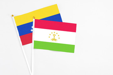 Tajikistan and Venezuela stick flags on white background. High quality fabric, miniature national flag. Peaceful global concept.White floor for copy space.