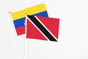 Trinidad And Tobago and Venezuela stick flags on white background. High quality fabric, miniature national flag. Peaceful global concept.White floor for copy space.