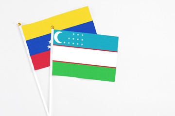 Uzbekistan and Venezuela stick flags on white background. High quality fabric, miniature national flag. Peaceful global concept.White floor for copy space.