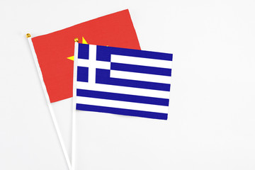 Obraz premium Greece and Vietnam stick flags on white background. High quality fabric, miniature national flag. Peaceful global concept.White floor for copy space.
