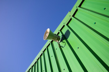 Fototapeta premium PA public address system speaker fixed to profiled metal clad building