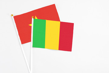Fototapeta premium Mali and Vietnam stick flags on white background. High quality fabric, miniature national flag. Peaceful global concept.White floor for copy space.