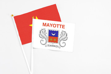 Mayotte and Vietnam stick flags on white background. High quality fabric, miniature national flag. Peaceful global concept.White floor for copy space.