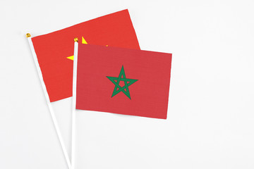 Morocco and Vietnam stick flags on white background. High quality fabric, miniature national flag. Peaceful global concept.White floor for copy space.