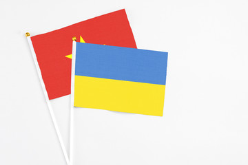 Ukraine and Vietnam stick flags on white background. High quality fabric, miniature national flag. Peaceful global concept.White floor for copy space.
