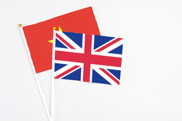 Fototapeta premium United Kingdom and Vietnam stick flags on white background. High quality fabric, miniature national flag. Peaceful global concept.White floor for copy space.