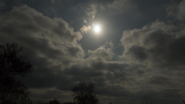 Timelapse of the full moon light illuminating the clouds from behind
