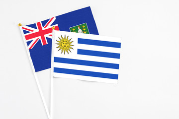 Uruguay and British Virgin Islands stick flags on white background. High quality fabric, miniature national flag. Peaceful global concept.White floor for copy space.