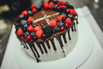 White cake with chocolate glaze and berrys, birthday cake in close up