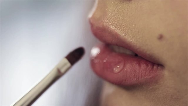 Female lips close-up. lipstick and lip gloss in makeup. Application. The concept of advertising lipstick, lip gloss, dentistry, plastic surgery, oral diseases, teeth