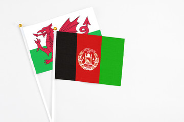 Afghanistan and Wales stick flags on white background. High quality fabric, miniature national flag. Peaceful global concept.White floor for copy space.