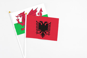 Albania and Wales stick flags on white background. High quality fabric, miniature national flag. Peaceful global concept.White floor for copy space.