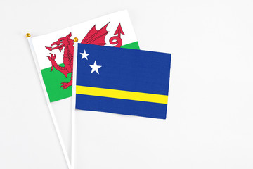 Curacao and Wales stick flags on white background. High quality fabric, miniature national flag. Peaceful global concept.White floor for copy space.