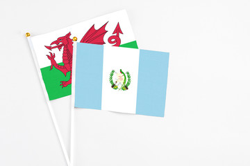 Guatemala and Wales stick flags on white background. High quality fabric, miniature national flag. Peaceful global concept.White floor for copy space.