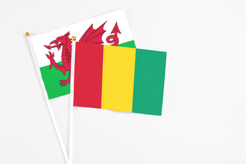 Guinea and Wales stick flags on white background. High quality fabric, miniature national flag. Peaceful global concept.White floor for copy space.