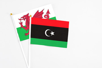 Libya and Wales stick flags on white background. High quality fabric, miniature national flag. Peaceful global concept.White floor for copy space.