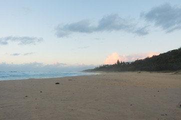 Sun rising over the horizon at a beach by a headland