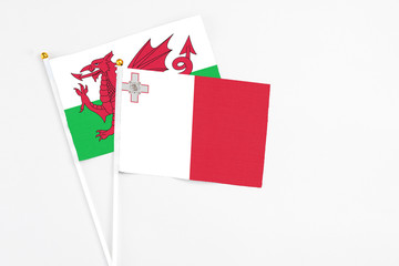 Malta and Wales stick flags on white background. High quality fabric, miniature national flag. Peaceful global concept.White floor for copy space.