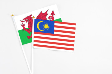 Malaysia and Wales stick flags on white background. High quality fabric, miniature national flag. Peaceful global concept.White floor for copy space.