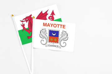 Mayotte and Wales stick flags on white background. High quality fabric, miniature national flag. Peaceful global concept.White floor for copy space.
