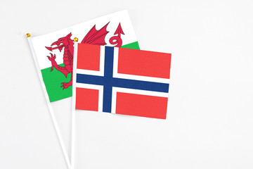 Norway and Wales stick flags on white background. High quality fabric, miniature national flag. Peaceful global concept.White floor for copy space.