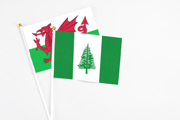 Norfolk Island and Wales stick flags on white background. High quality fabric, miniature national flag. Peaceful global concept.White floor for copy space.